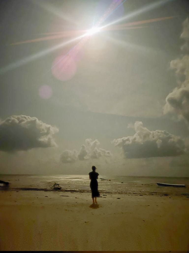 Frau am Meer, blickt in das Licht über dem Wasser